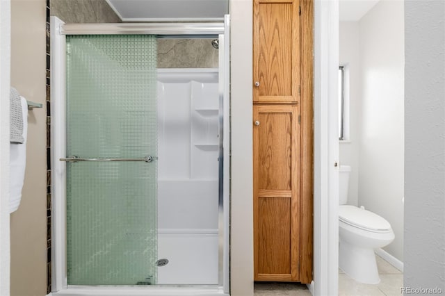 bathroom featuring toilet, an enclosed shower, and tile patterned flooring