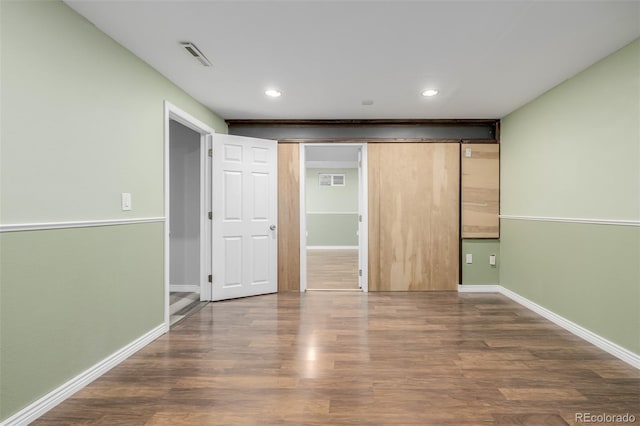 unfurnished bedroom featuring a barn door and dark hardwood / wood-style flooring