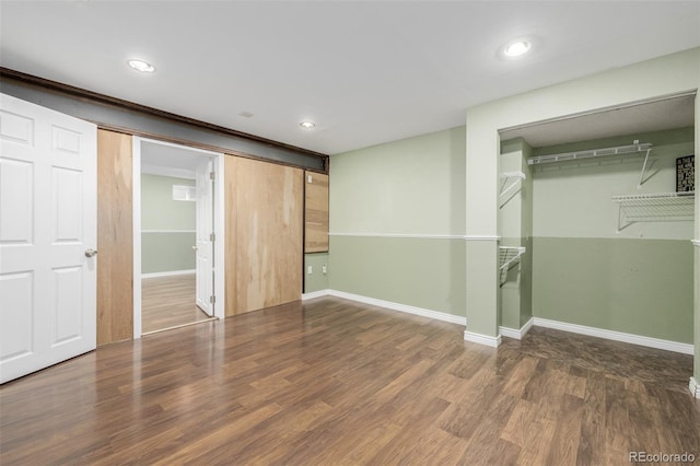 unfurnished bedroom with dark wood-type flooring, a closet, and a barn door