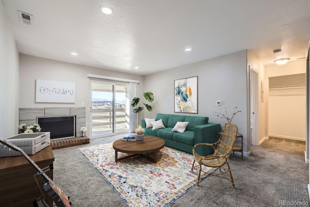 carpeted living room with baseboards, visible vents, a textured ceiling, a brick fireplace, and recessed lighting