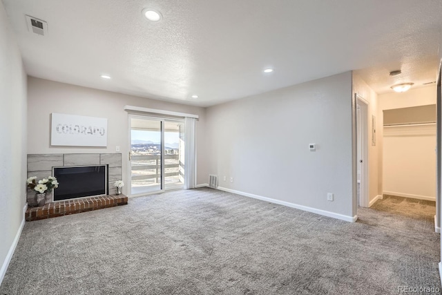 unfurnished living room with carpet floors, a textured ceiling, and a brick fireplace