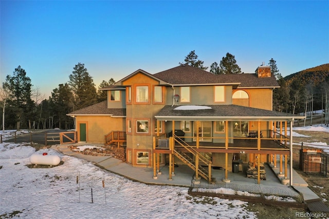 snow covered back of property with a patio area