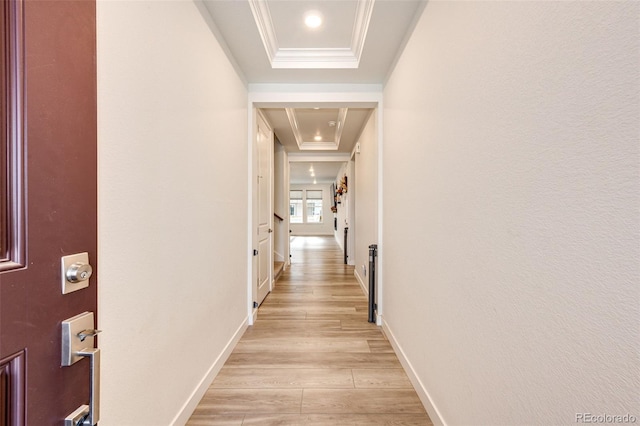 corridor with a raised ceiling, crown molding, and light hardwood / wood-style flooring