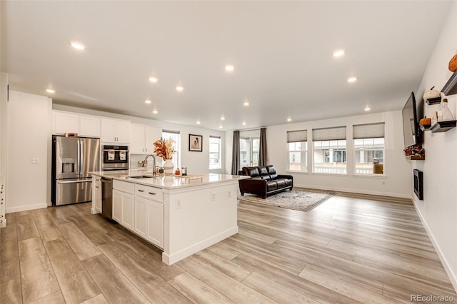 kitchen with stainless steel appliances, white cabinetry, a kitchen island with sink, and sink