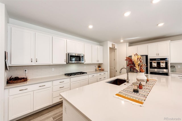 kitchen with sink, white cabinets, stainless steel appliances, and light hardwood / wood-style floors