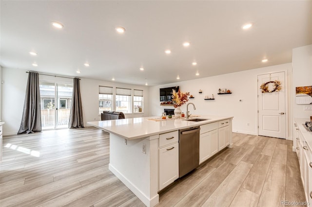 kitchen featuring dishwasher, an island with sink, light hardwood / wood-style floors, and sink