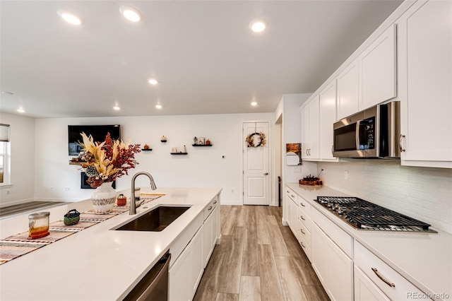 kitchen with white cabinets, light hardwood / wood-style floors, sink, and appliances with stainless steel finishes