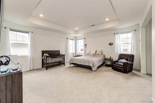 carpeted bedroom featuring a tray ceiling, multiple windows, and crown molding