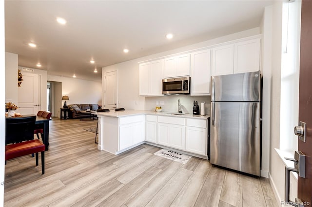 kitchen featuring sink, light wood-type flooring, white cabinetry, and stainless steel appliances