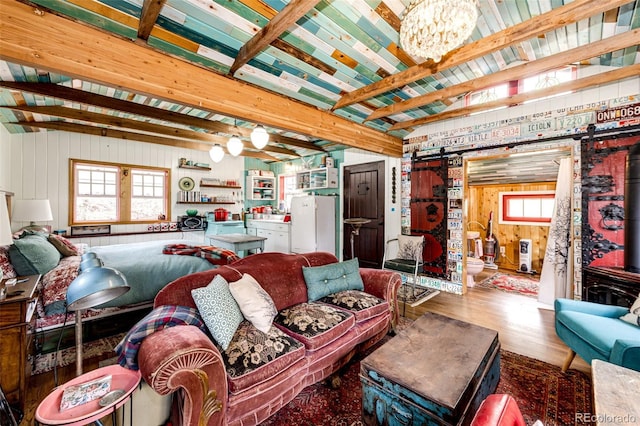 12346 Bear Haven Rd, Conifer, CO 80433 - living area with a barn door, beamed ceiling, wood finished floors, plenty of natural light, and wooden walls