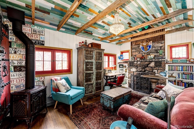 12346 Bear Haven Rd, Conifer, CO 80433 - living area featuring a wood stove, wood finished floors, plenty of natural light, wood walls, and wooden ceiling with exposed beams