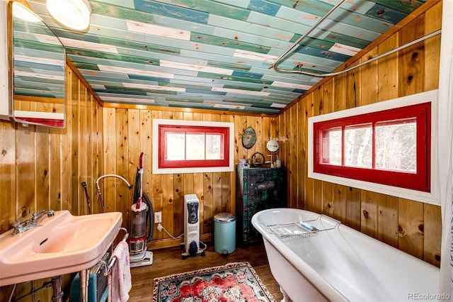 12346 Bear Haven Rd, Conifer, CO 80433 - bathroom with wood finished floors, a freestanding tub, plenty of natural light, a sink, and wooden walls