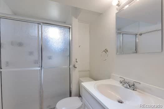 bathroom with vanity, toilet, and a shower with shower door