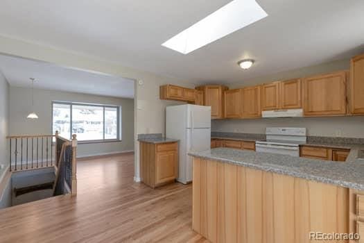 kitchen featuring light hardwood / wood-style flooring, pendant lighting, white appliances, and a skylight