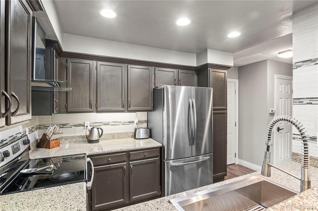 943 S Fairplay St, Aurora, CO 80012 - kitchen with appliances with stainless steel finishes, a sink, dark brown cabinetry, light stone counters, and recessed lighting