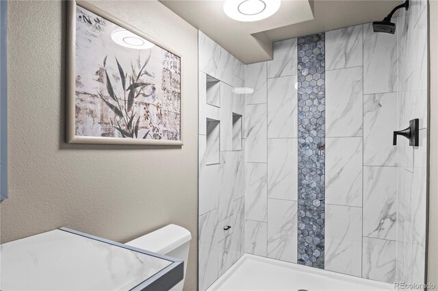 943 S Fairplay St, Aurora, CO 80012 - bathroom with tiled shower, toilet, and a textured wall