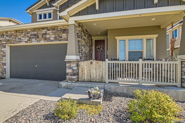 property entrance featuring driveway, stone siding, covered porch, and board and batten siding