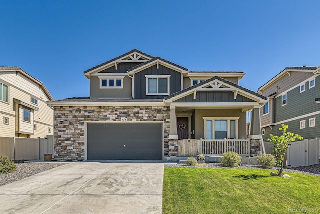 craftsman house with driveway, fence, a porch, board and batten siding, and a front yard