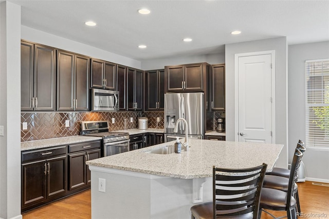 15895 Columbine St, Thornton, CO 80602 - kitchen with appliances with stainless steel finishes, light wood finished floors, a breakfast bar area, tasteful backsplash, and recessed lighting