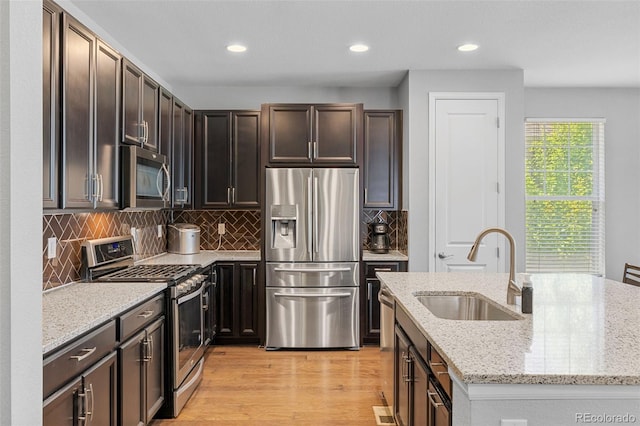 15895 Columbine St, Thornton, CO 80602 - kitchen with stainless steel appliances, recessed lighting, light stone counters, light wood finished floors, and a center island with sink