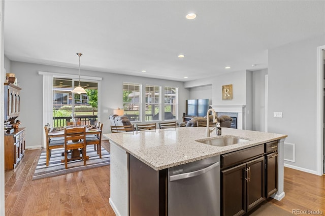 15895 Columbine St, Thornton, CO 80602 - kitchen with dishwasher, open floor plan, light wood-style flooring, dark brown cabinets, and a fireplace