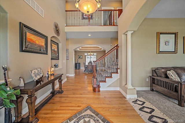8655 E 130th Ave, Thornton, CO 80602 - entryway featuring light wood-style flooring, baseboards, a high ceiling, arched walkways, and ornate columns