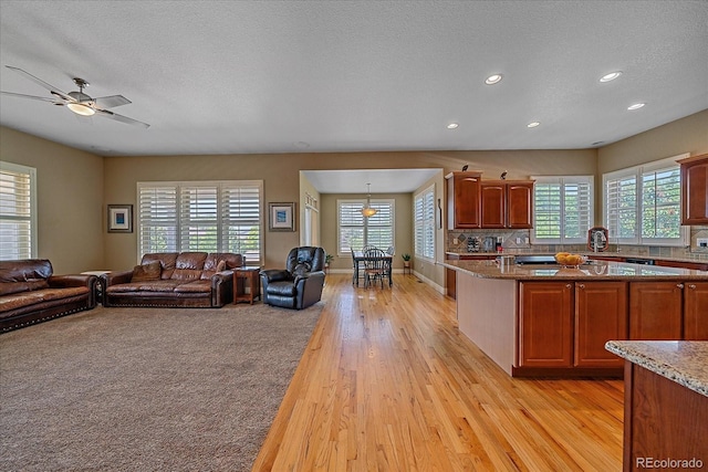 8655 E 130th Ave, Thornton, CO 80602 - kitchen featuring light wood finished floors, open floor plan, recessed lighting, light stone counters, and ceiling fan