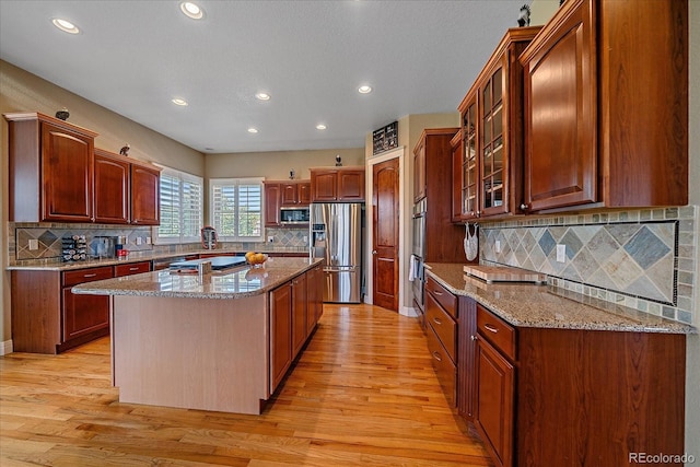 8655 E 130th Ave, Thornton, CO 80602 - kitchen featuring stainless steel appliances, light wood finished floors, a kitchen island, recessed lighting, and backsplash