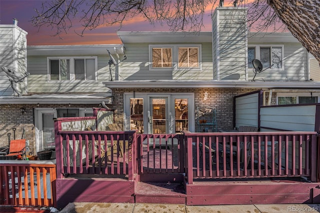 back house at dusk featuring a wooden deck