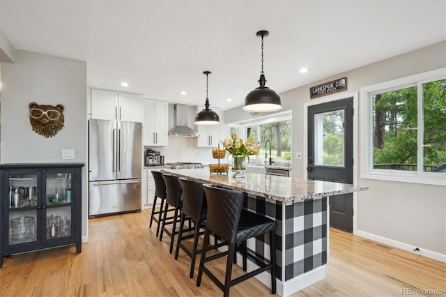 7312 Marshall Rd, Larkspur, CO 80118 - kitchen with freestanding refrigerator, wall chimney range hood, healthy amount of natural light, light stone counters, and recessed lighting