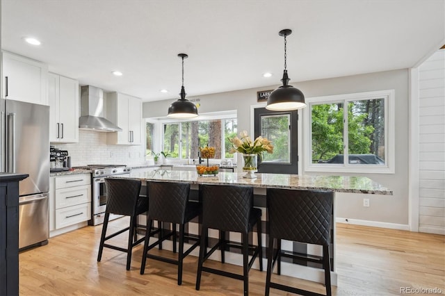 7312 Marshall Rd, Larkspur, CO 80118 - kitchen with wall chimney range hood, stainless steel appliances, plenty of natural light, white cabinetry, and recessed lighting