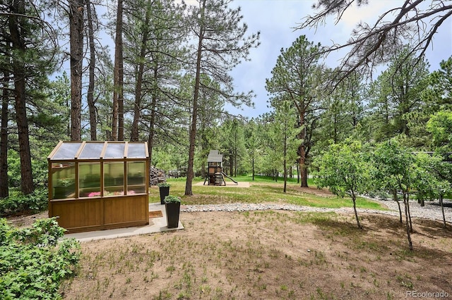 7312 Marshall Rd, Larkspur, CO 80118 - view of grassy yard featuring a greenhouse, an outbuilding, and a playground