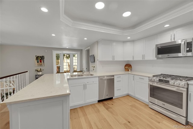 kitchen featuring appliances with stainless steel finishes, a sink, a peninsula, white cabinets, and recessed lighting
