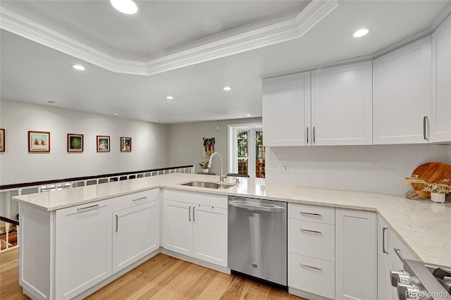 kitchen featuring dishwasher, a sink, stove, a peninsula, and white cabinetry