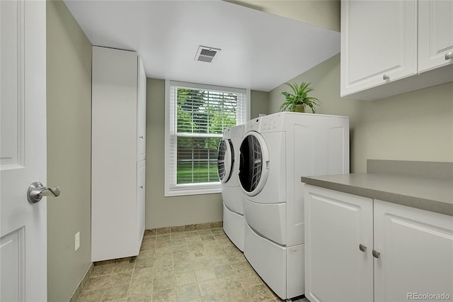 laundry room featuring washer and clothes dryer, cabinet space, baseboards, and stone finish flooring