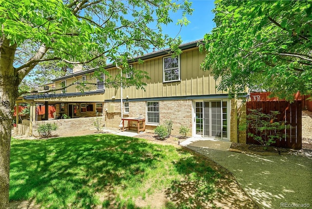 rear view of property featuring a yard, a patio area, and brick siding