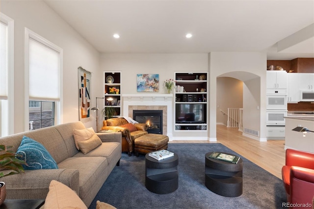 652 Ulster Way, Denver, CO 80230 - living room featuring arched walkways, built in features, light wood-type flooring, a fireplace, and recessed lighting