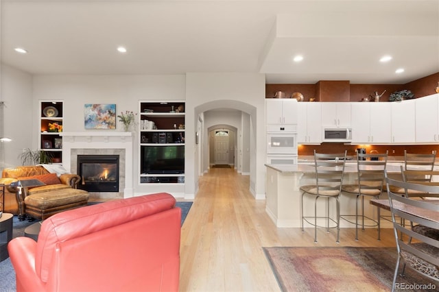 652 Ulster Way, Denver, CO 80230 - living area with arched walkways, light wood-style flooring, recessed lighting, built in shelves, and a glass covered fireplace