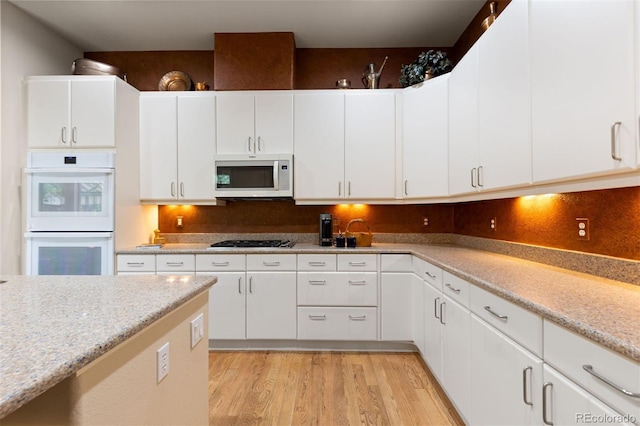 652 Ulster Way, Denver, CO 80230 - kitchen featuring white appliances, light wood-style floors, decorative backsplash, and white cabinetry