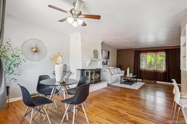 3871 W Saratoga Ave, Littleton, CO 80123 - dining area featuring a glass covered fireplace, wood finished floors, and ceiling fan