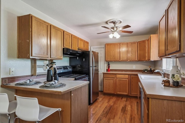 3871 W Saratoga Ave, Littleton, CO 80123 - kitchen featuring a peninsula, under cabinet range hood, stainless steel range with electric cooktop, a ceiling fan, and light wood-type flooring