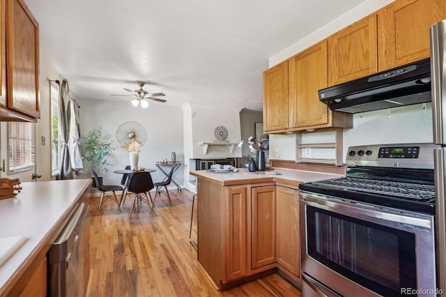 3871 W Saratoga Ave, Littleton, CO 80123 - kitchen featuring appliances with stainless steel finishes, under cabinet range hood, a peninsula, light wood-style flooring, and light countertops