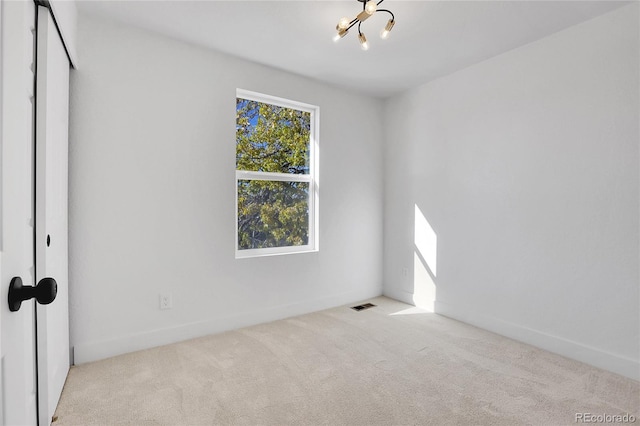 unfurnished bedroom featuring a notable chandelier and light carpet