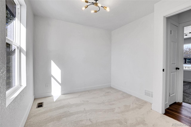 carpeted empty room with a chandelier