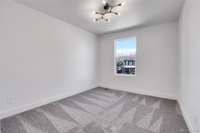 carpeted spare room featuring a notable chandelier