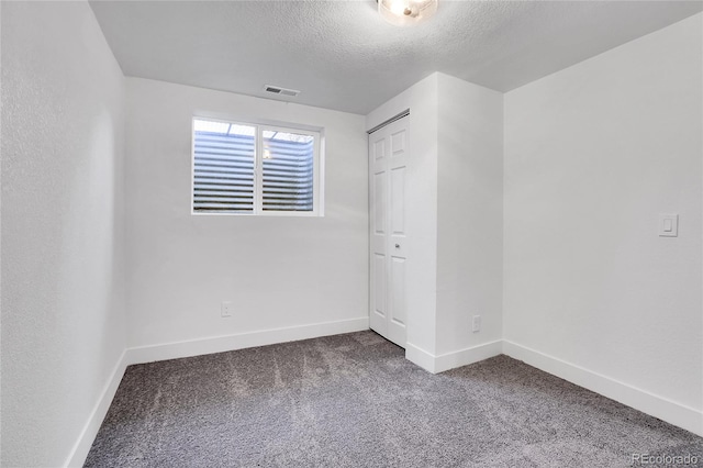 unfurnished room with carpet flooring and a textured ceiling