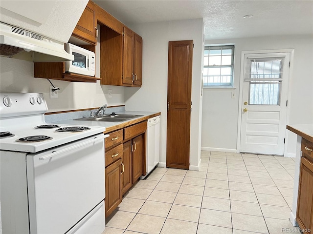 kitchen featuring sink, a textured ceiling, white appliances, light tile patterned floors, and exhaust hood