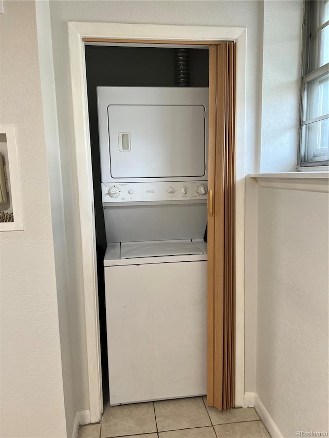 laundry room with stacked washer / drying machine and light tile patterned floors