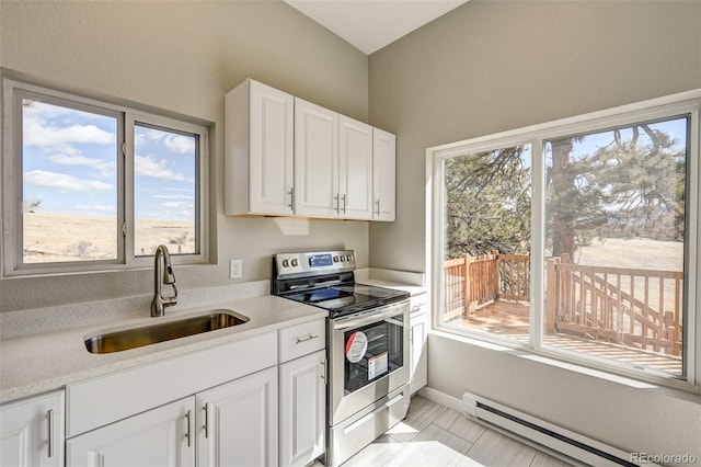 kitchen with a wealth of natural light, stainless steel electric stove, a baseboard heating unit, sink, and white cabinetry