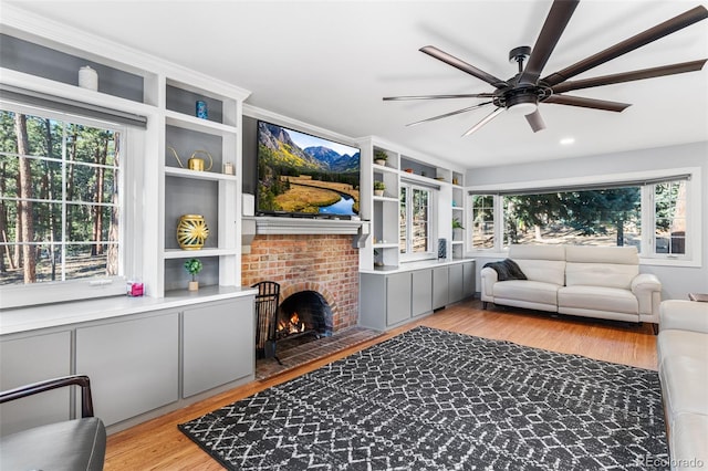 living area featuring a fireplace, plenty of natural light, wood finished floors, and ceiling fan